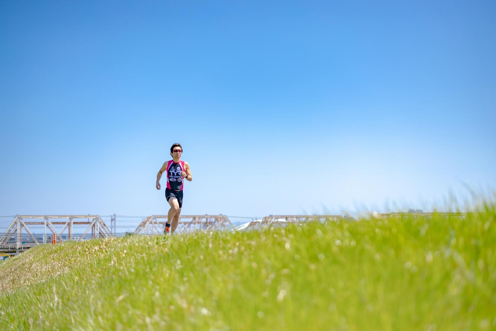 Runner running on grass under a blue sky