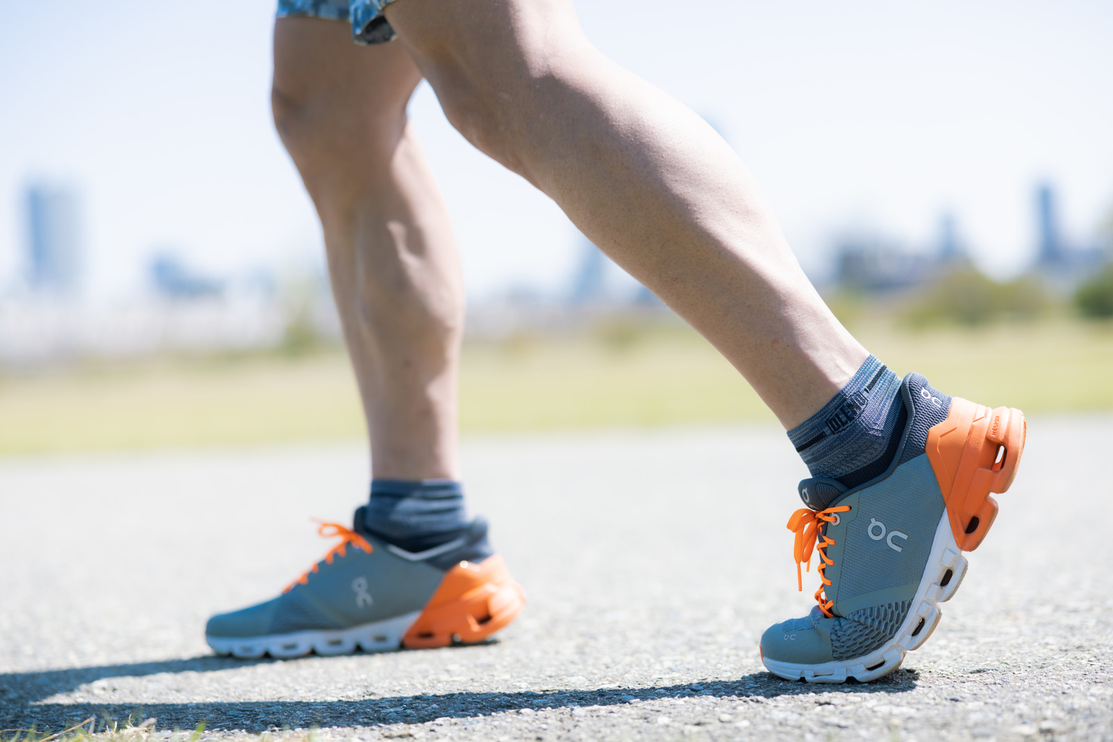Runner wearing orange and blue running shoes on an asphalt road